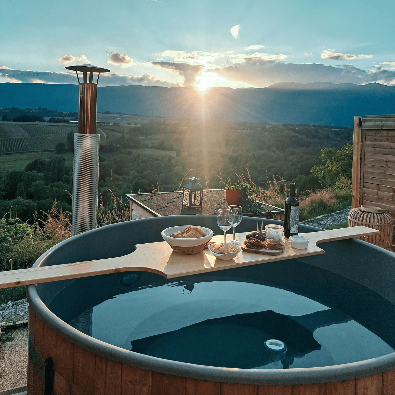 Un bain nordique chauffé au bois, avec vin et produits locaux, face aux vignes et au Jura au coucher du soleil